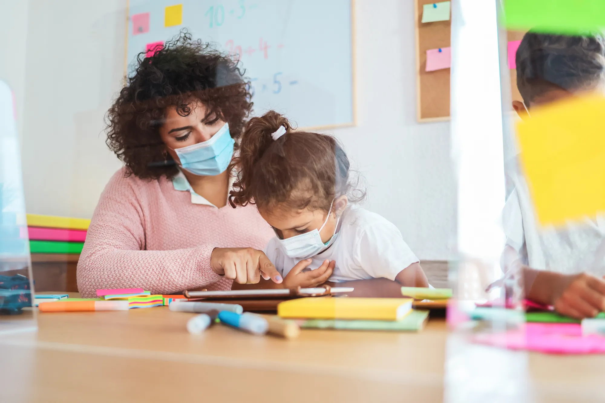 Teacher using tablet with children in preschool during coronavirus outbreak.