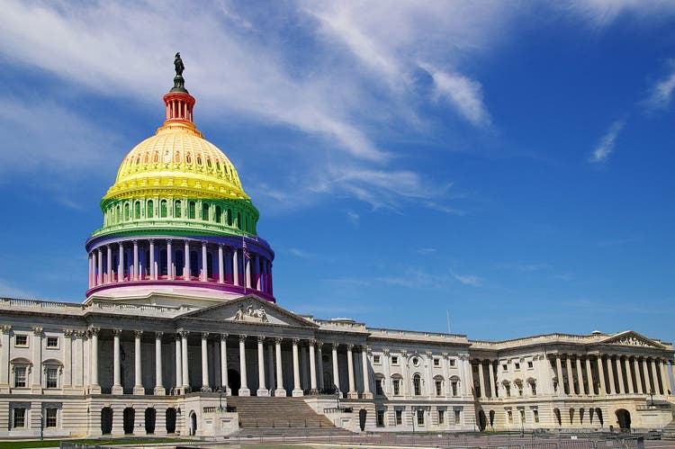 Capitol building with rainbow colors on the top of it.