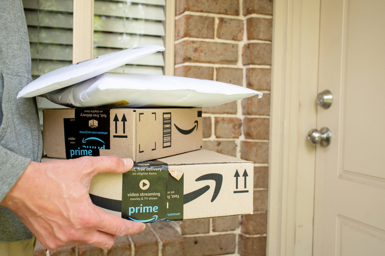 Amazon Prime boxes being delivered to a door. 