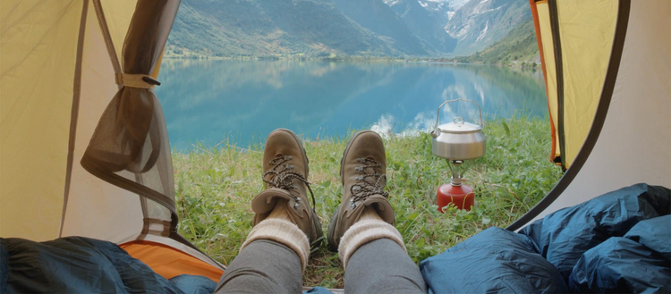 View from inside a tent looking out onto water and mountains. 