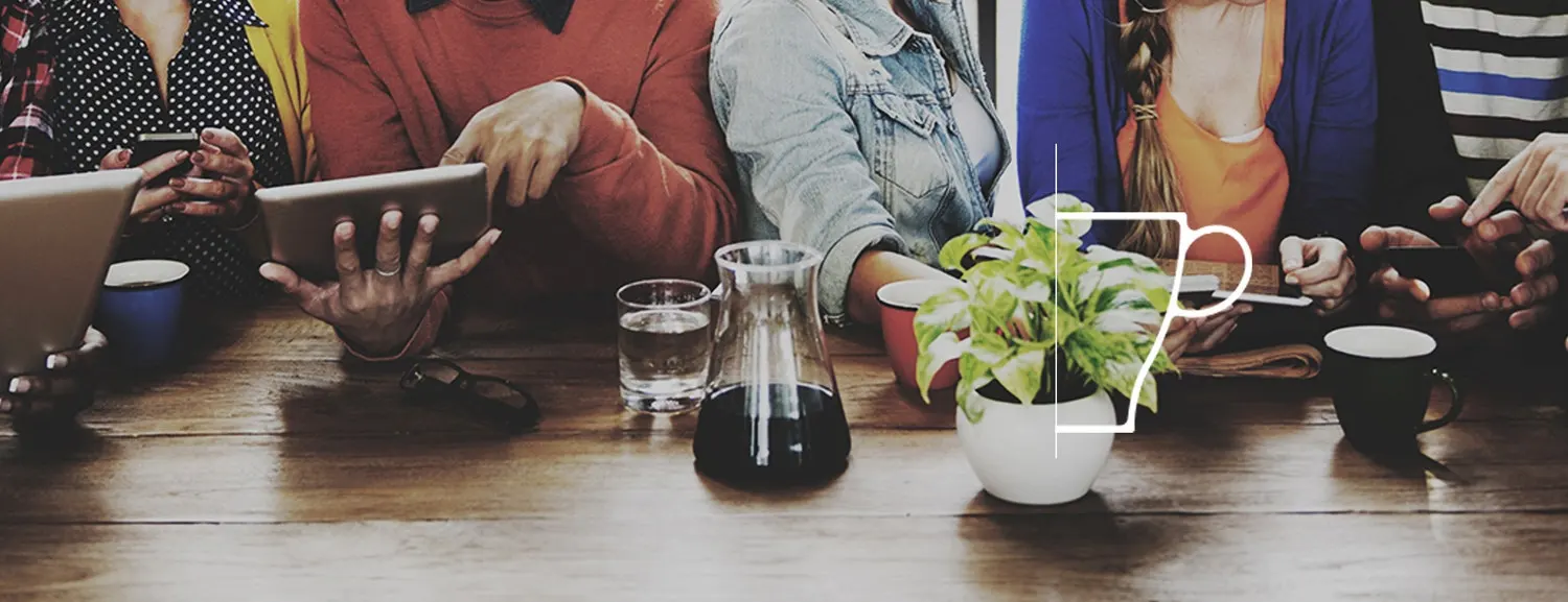 Group of people at a table with tablets and phones in their hands.