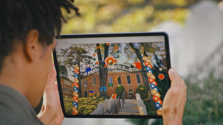 Man holding an ipad looking at a colorful screen. 