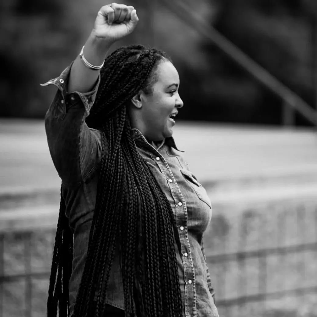 Black and white photo of woman holding her fist in the air. 