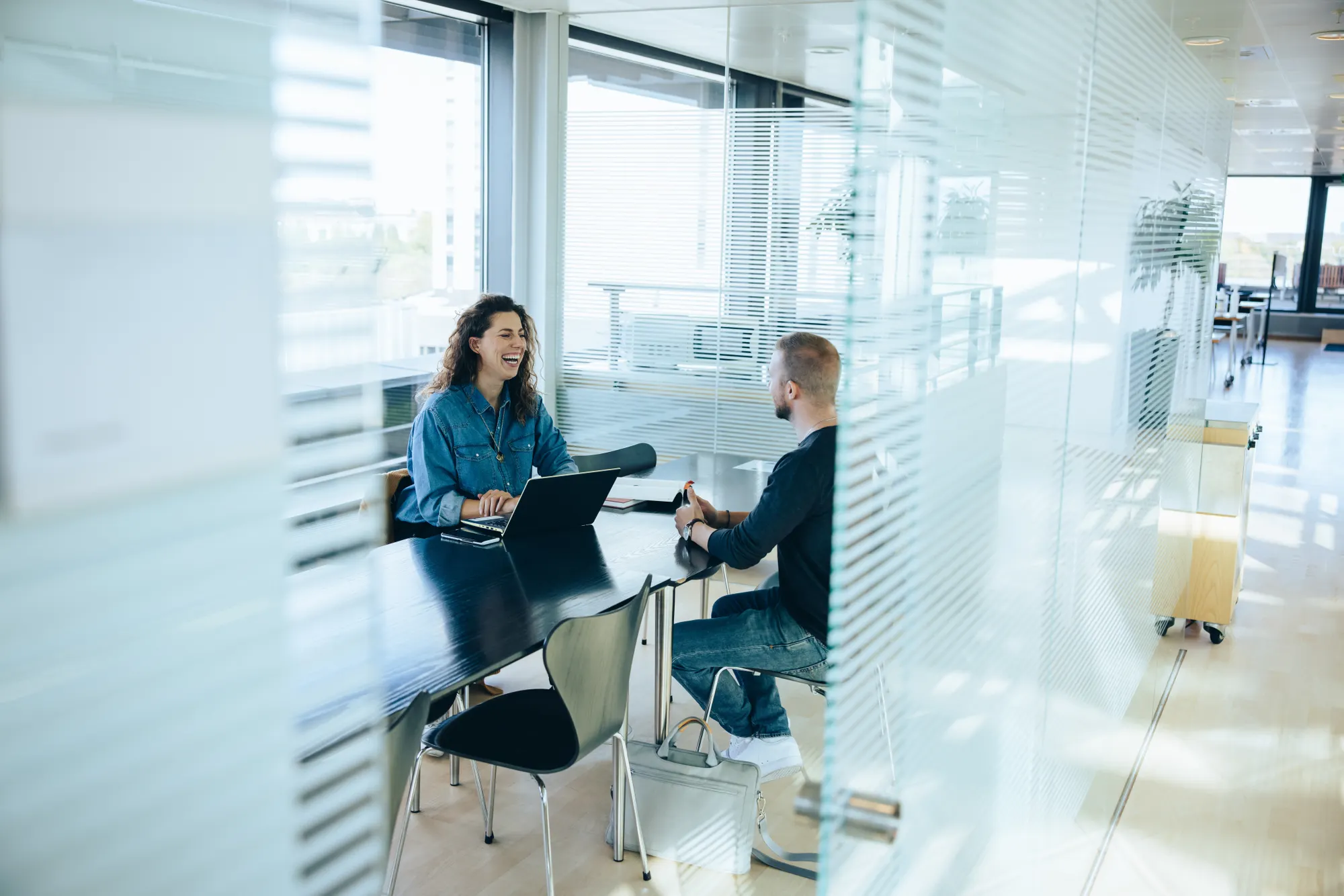 Two people sitting in an office space laughing.