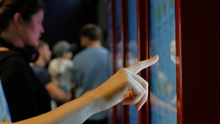 Close up photo of a finger pushing a touch screen. 