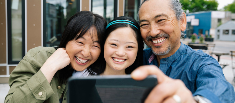 Family looking into a phone smiling and taking a selfie. 