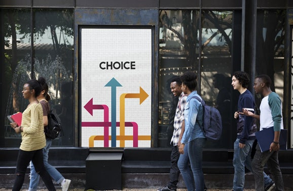 People walking past a sign with arrows depicting different choices. 