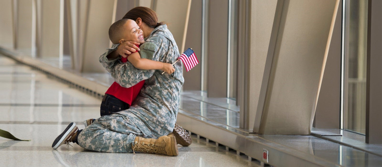 Veteran hugging a small child holding a flag. 