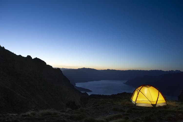 Photo of a lit up tent with the sky in the background.