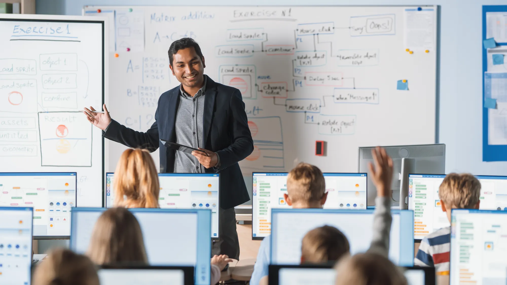 Elementary School Class: Teacher Uses Interactive Digital Whiteboard, Explains Lesson to Diverse Group of Smart Children.