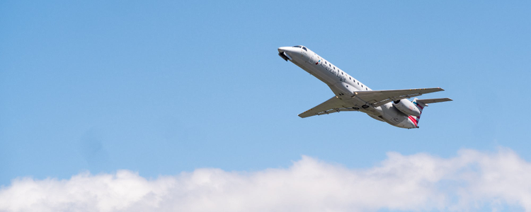 Photograph of plane flying in the clouds against a blue sky. 