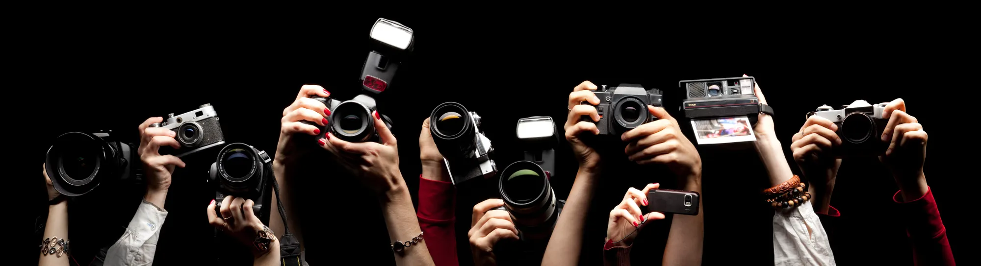Raised hands holding different photocameras.