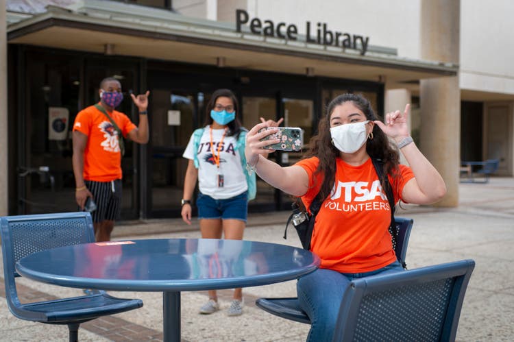 Students posing for a selfie outside of the Peace Library on UTSA's campus.