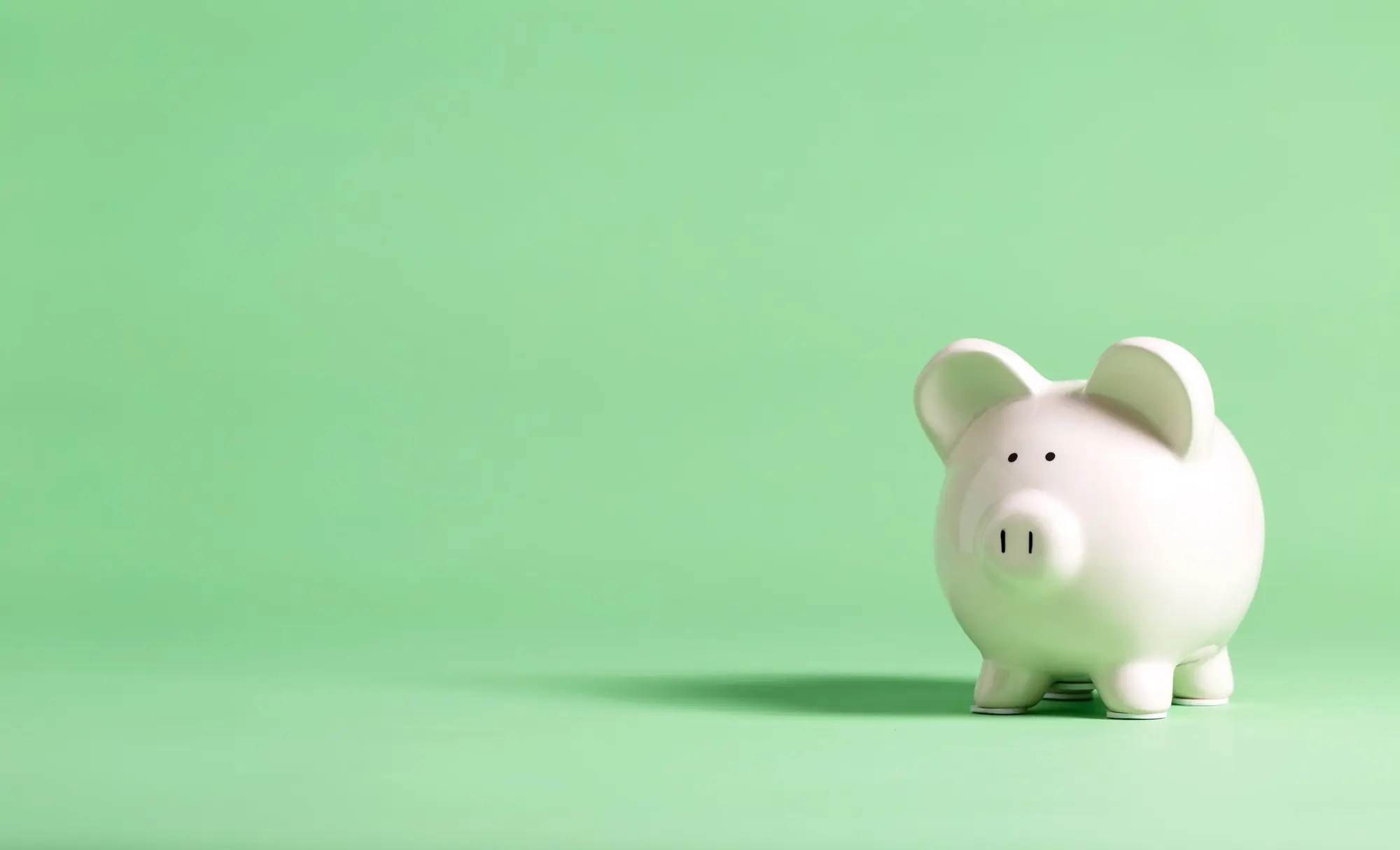 White piggy bank against a green background. 