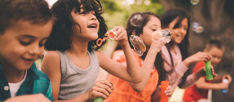 Five children blowing bubbles.