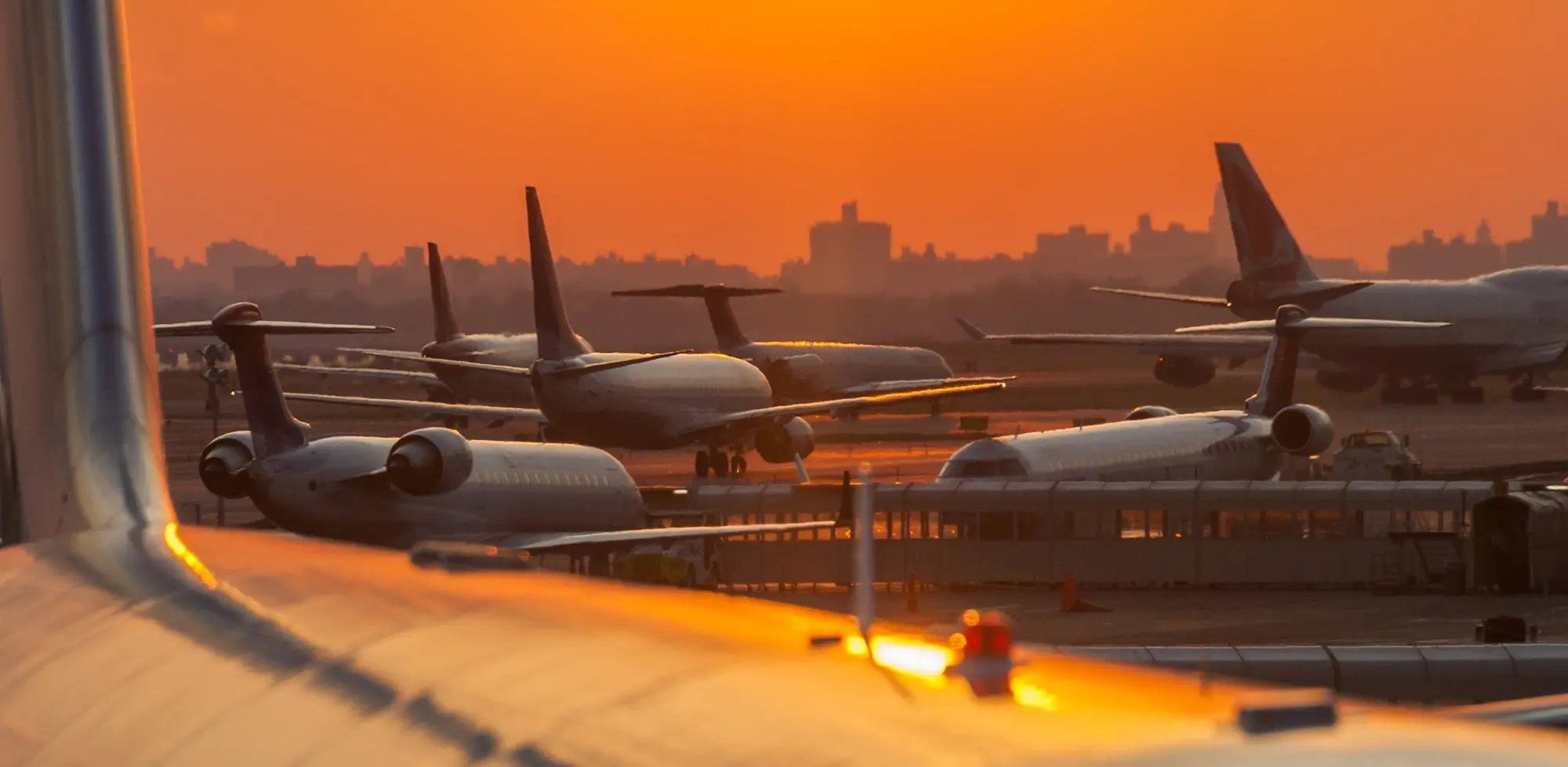 Image of several airplanes at an airport at sunset. 