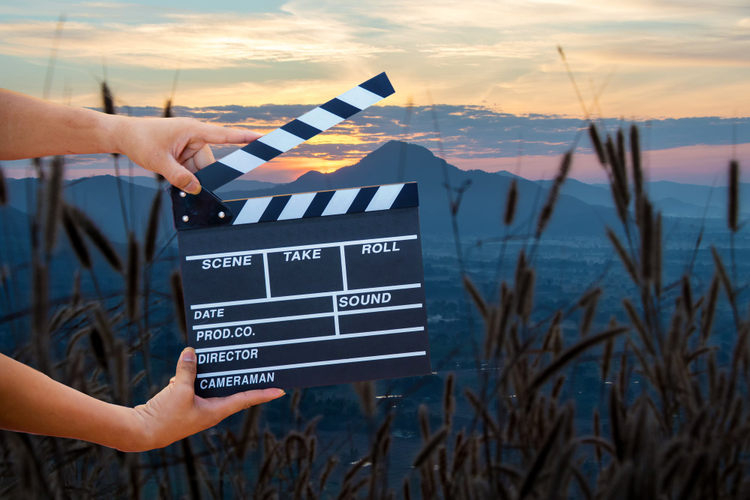 Man hands holding movie clapper isolated on nature background. Shown slate board. use the colors white and black.Realistic movie clapperboard.