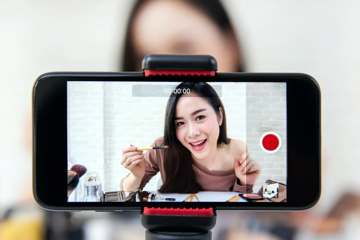 Close up image of a phone recording a woman doing her makeup.