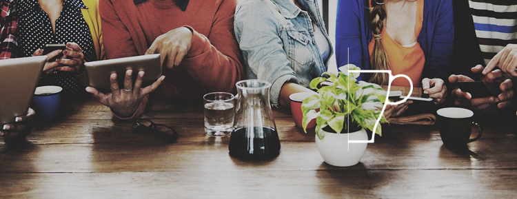 Group of people on devices at a table.