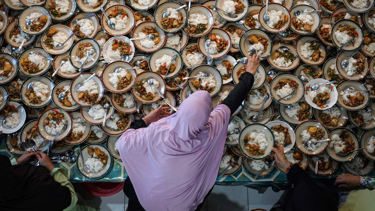 Plates of food stacked on top of eachother spread out over a table. 