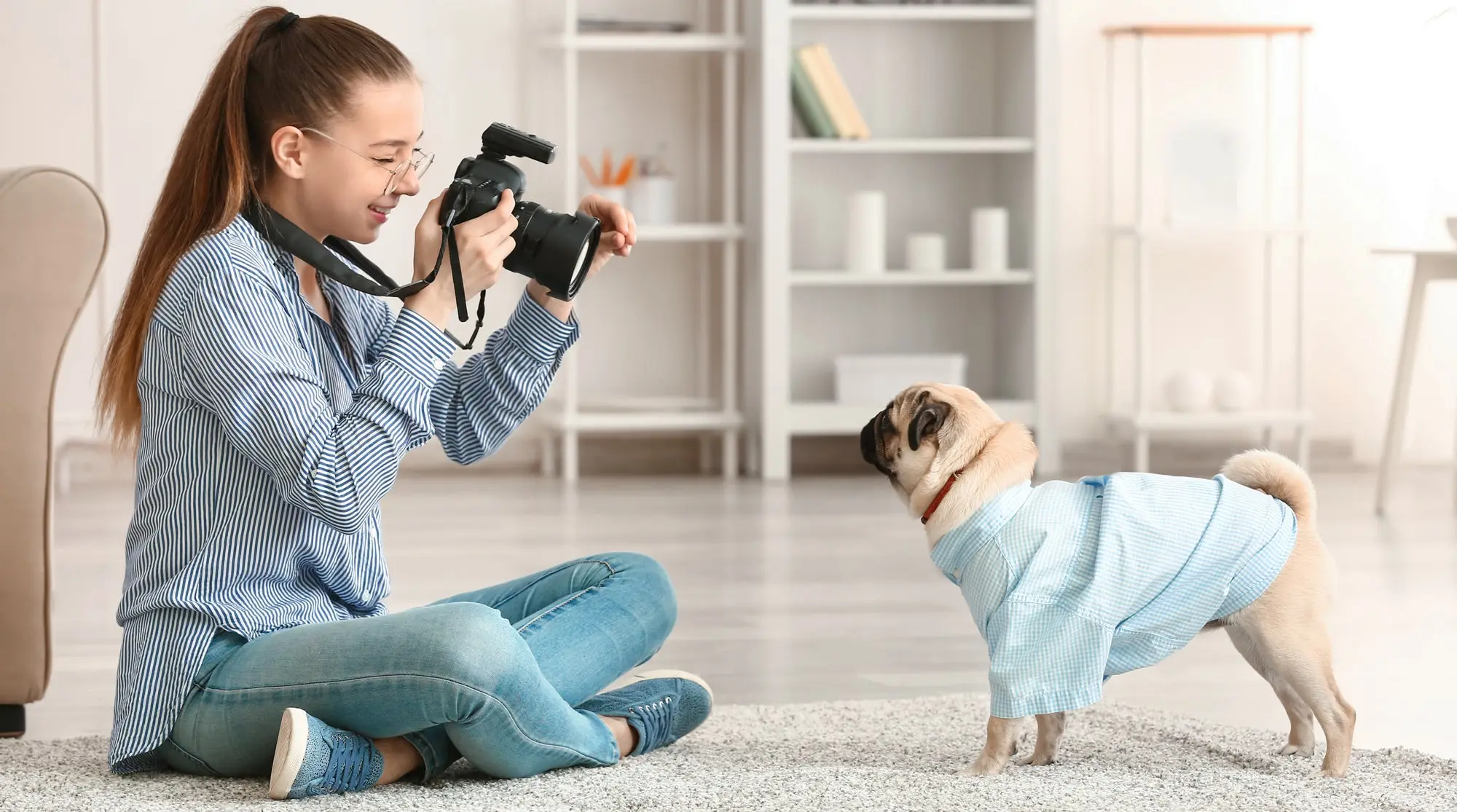 Girl taking a picture of a pug. 