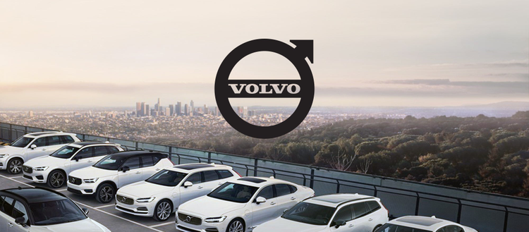 Volvo symbol above a line of white Volvo vehicles. 