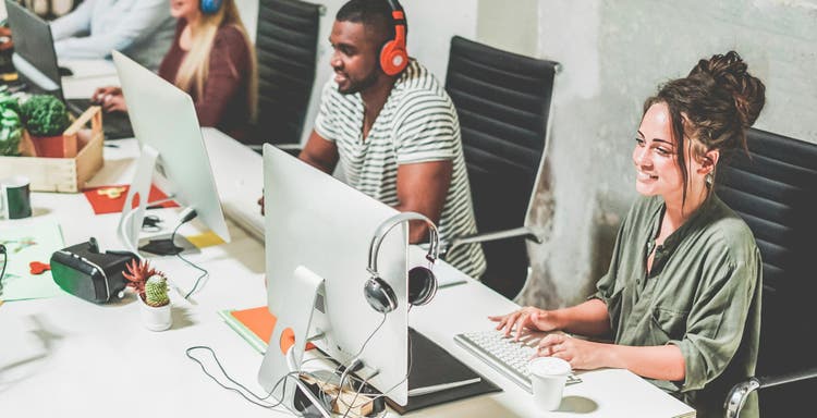 Young trendy teamwork using computer in creative coworking office.