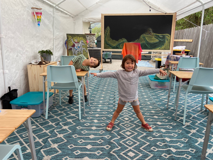 The outdoor classroom, with desks that are socially distanced. Rae and Kai are in the photo smiling.