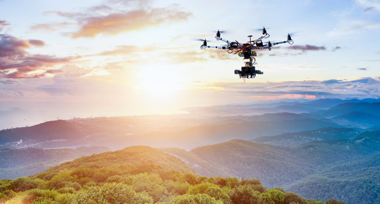 The drone with the professional camera takes pictures of the misty mountains at sunset.