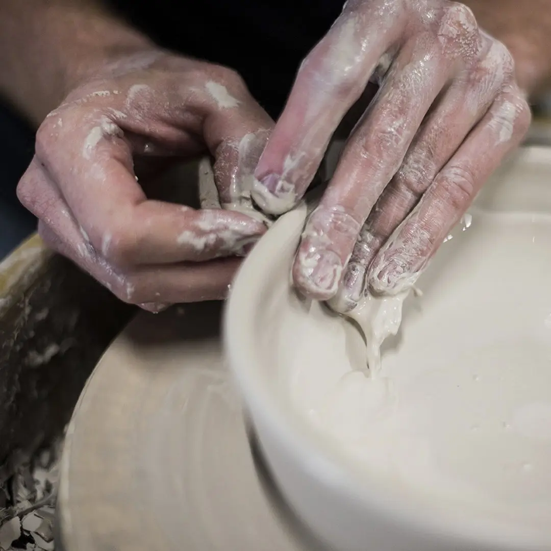 Hands making pottery.