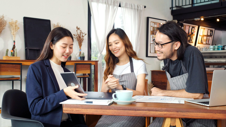 Young Asian business woman discussing about financial planning with small business owner at cafe coffee shop.
