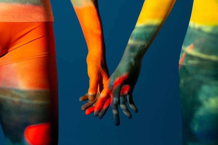 Closeup of couples hands with projector lights on them. 