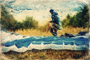 Photograph in a damaged film style of a man with a parachute.