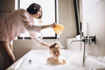 Photograph of a woman bathing a child.