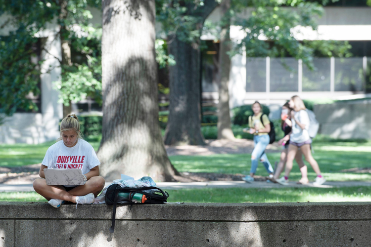 Student outside on a laptop. 