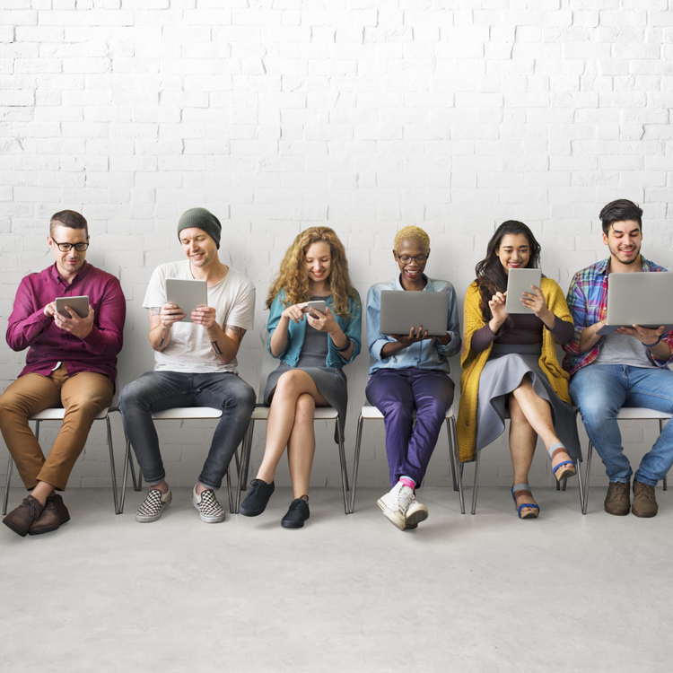 Image of people sitting on chairs, with a laptop, mobile device or tablet in hand.