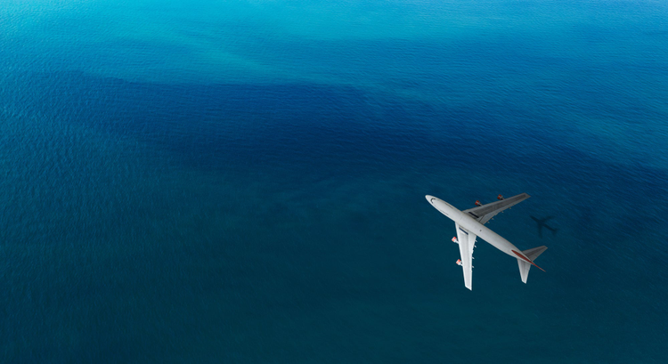 Airplane flying over blue water.