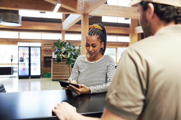 Smiling businesswoman digitally signing for a courier delivery.