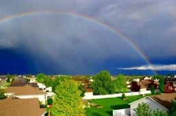 A photo of a rainbow above a cul-de-sac.
