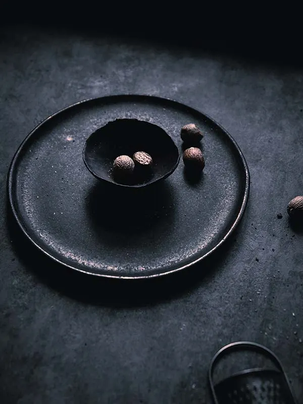 Macro photography of nutmeg seeds placed inside ceramic dishware.
