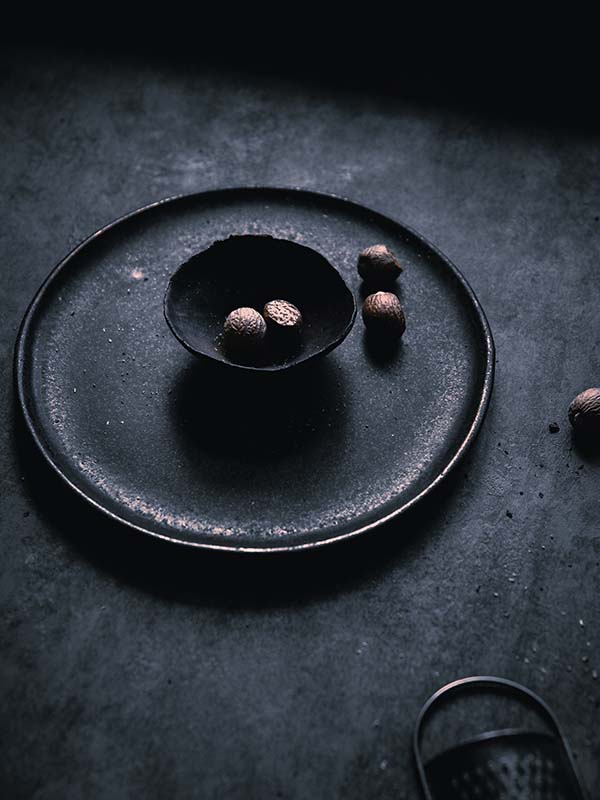 Macro photography of nutmeg seeds placed inside ceramic dishware.
