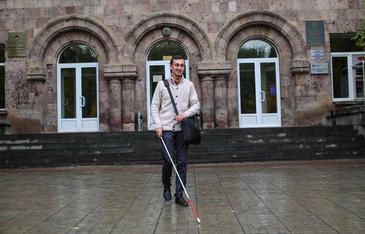 Adobe employee Sipan Asatryan walking outside. He is using his white cane.