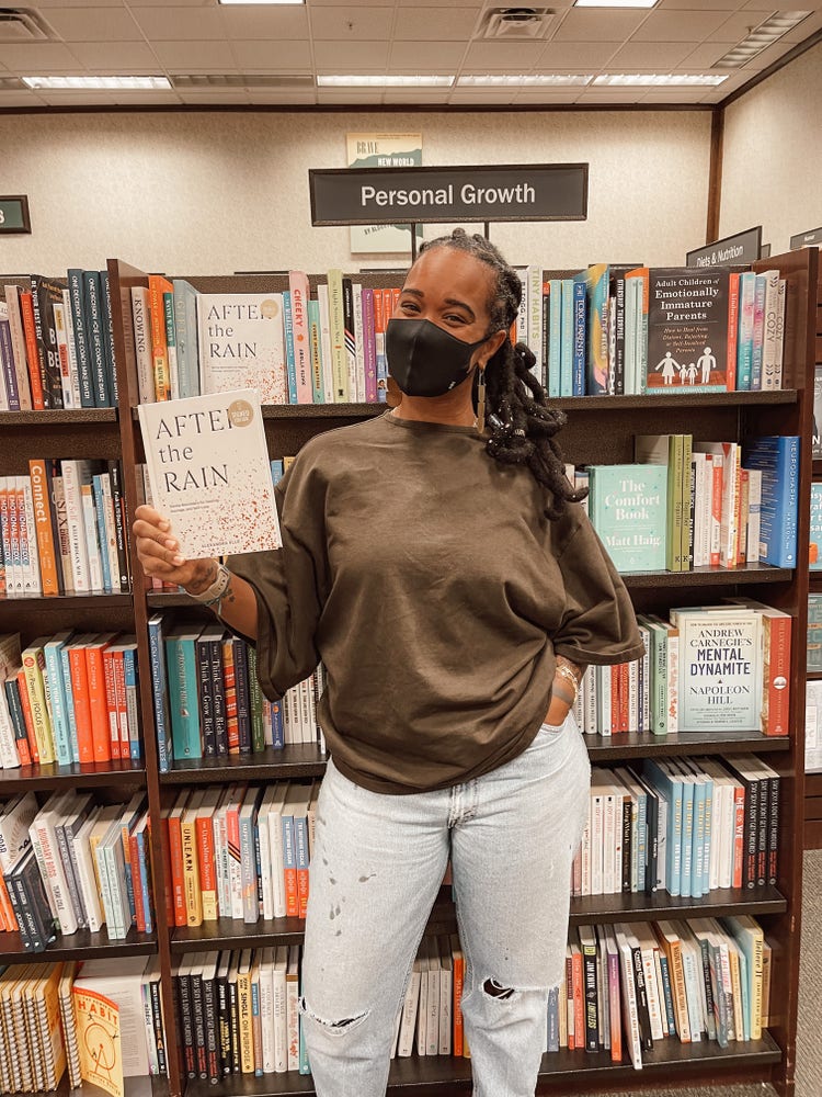 Alex Elle in a library holding a book she wrote.