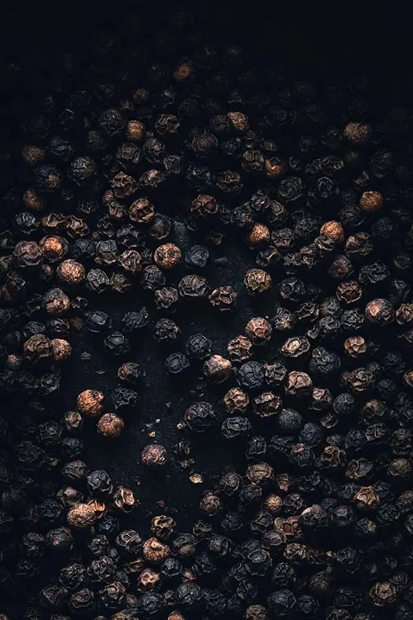 An overhead shot of peppercorns on a white table using a standard 35mm lens.