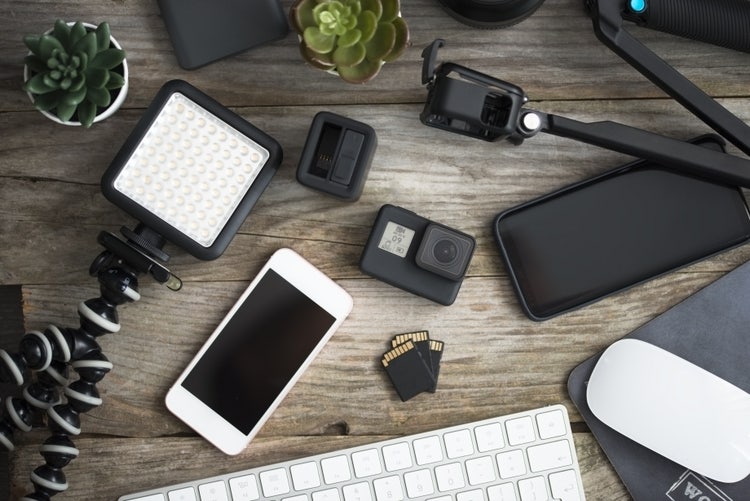 Top view of photo and video equipment on wooden table, action cam and accessories prepared for shooting.