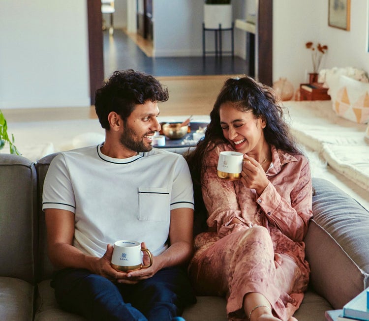 Radhi Devlukia-Shetty and her husband sitting on the couch.