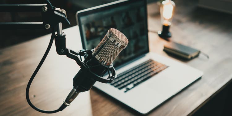 Home studio podcast interior. Microphone, laptop and on air lamp on the table, close-up.