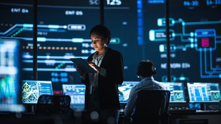 Young Multiethnic Female Government Employee Uses Tablet Computer in System Control Monitoring Center.