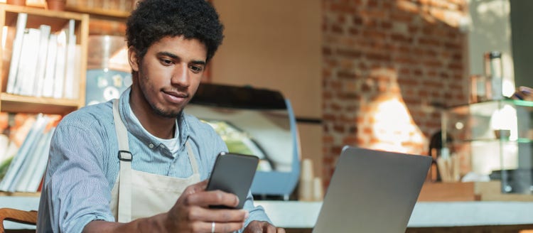 Man looking at his phone and laptop