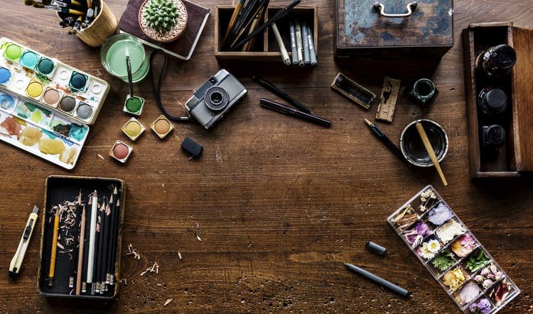 Aerial view of artistic equipment and painting tools on wooden table.